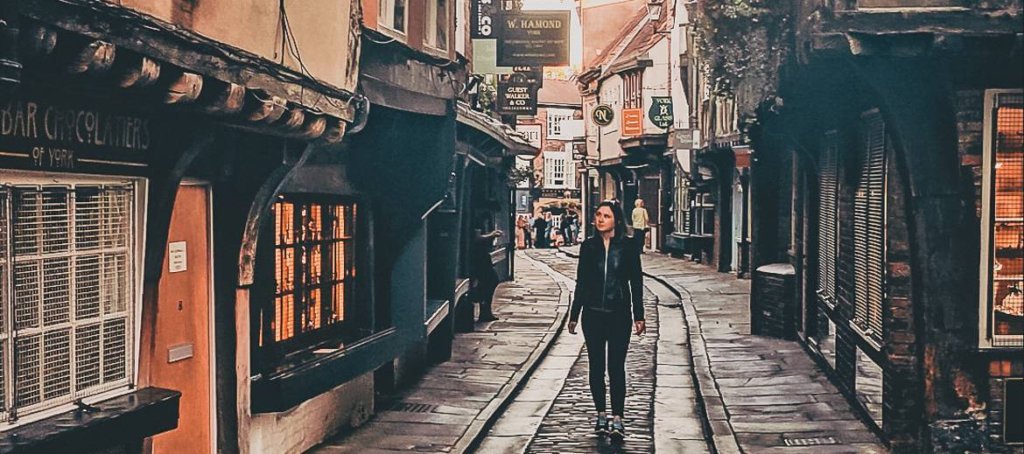 brunette girl in black leather coat exploring the shambles in York, England - York Overnight Stay