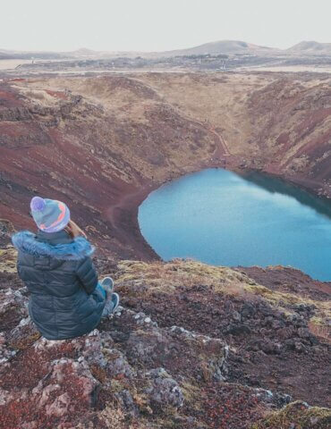 girl sitting near turquoise crater lake - is Iceland worth visiting