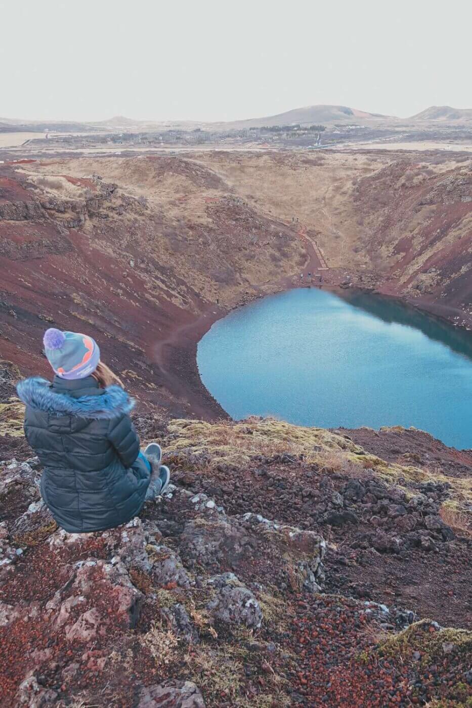 girl sitting near turquoise crater lake - is Iceland worth visiting