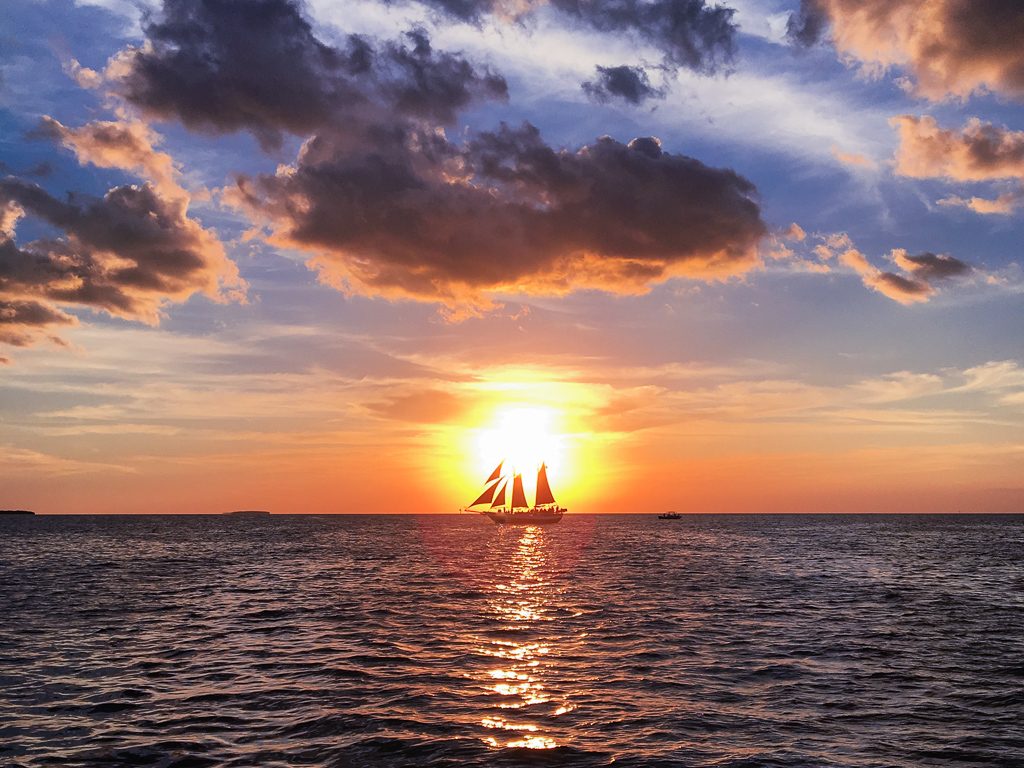 boat in front of setting sun - how to travel more