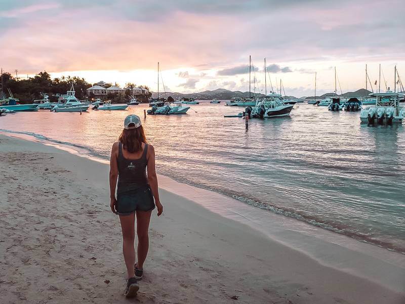 girl strolling along Cruz Bay Beach during sunset