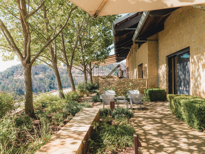 Stone winery building and tasting room with patio overlooking Howell Mountain vineyard - wineries to visit in Napa Valley