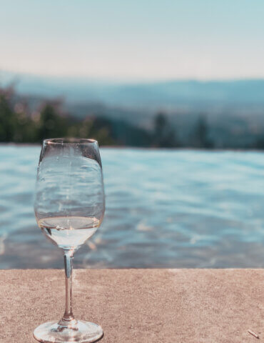 wine glass in front of infinity pool and mountainous cade winery view - wineries to visit in napa
