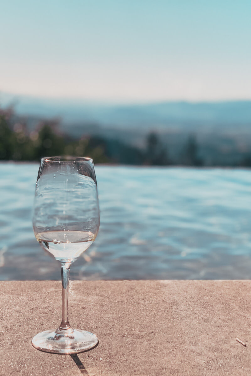 wine glass in front of infinity pool and mountainous cade winery view - wineries to visit in napa