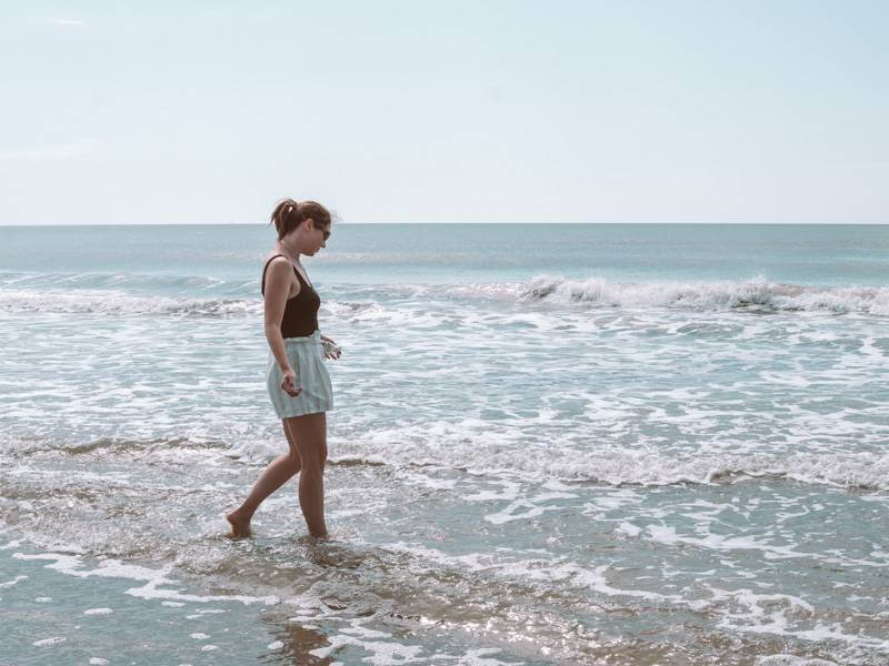 Girl tip-toing through the seafoam at the Isle of Palms - romantic things to do in Charleston, SC
