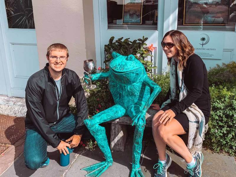 a man and women crouching next to a giant turquoise frog