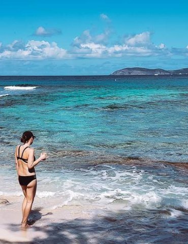 girl in black swimsuit standing on caribbean beach