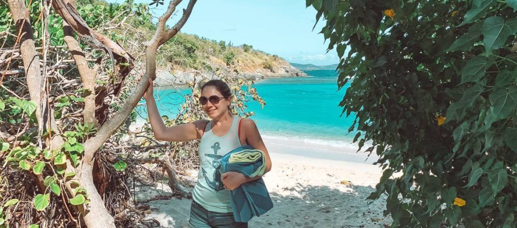 brunette girl wearing sunglasses holding towel at jumbie bay in st john usvi