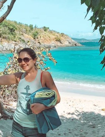 brunette girl wearing sunglasses holding towel at jumbie bay in st john usvi