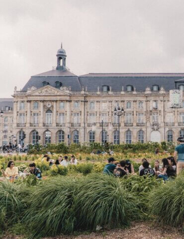 People sitting in garden near riverfront in Bordeaux - cost of a trip to France
