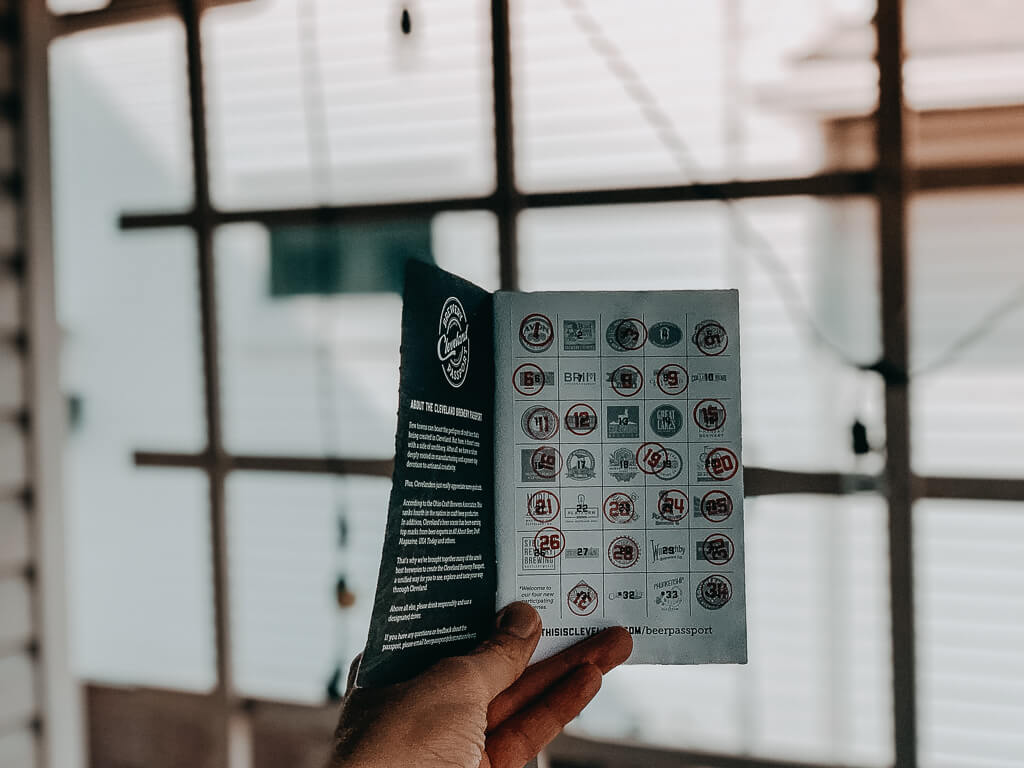 person holding cleveland brewery passport in front of terrace