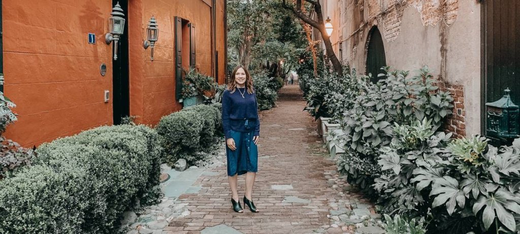 girl in romantic charleston alley way wearing purple sweater over purple shirtdress