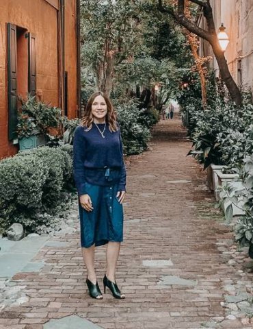 girl in romantic charleston alley way wearing purple sweater over purple shirtdress