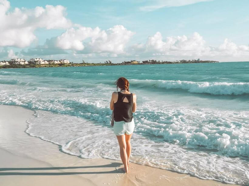 girl walking down a beach as sea foam rolls in