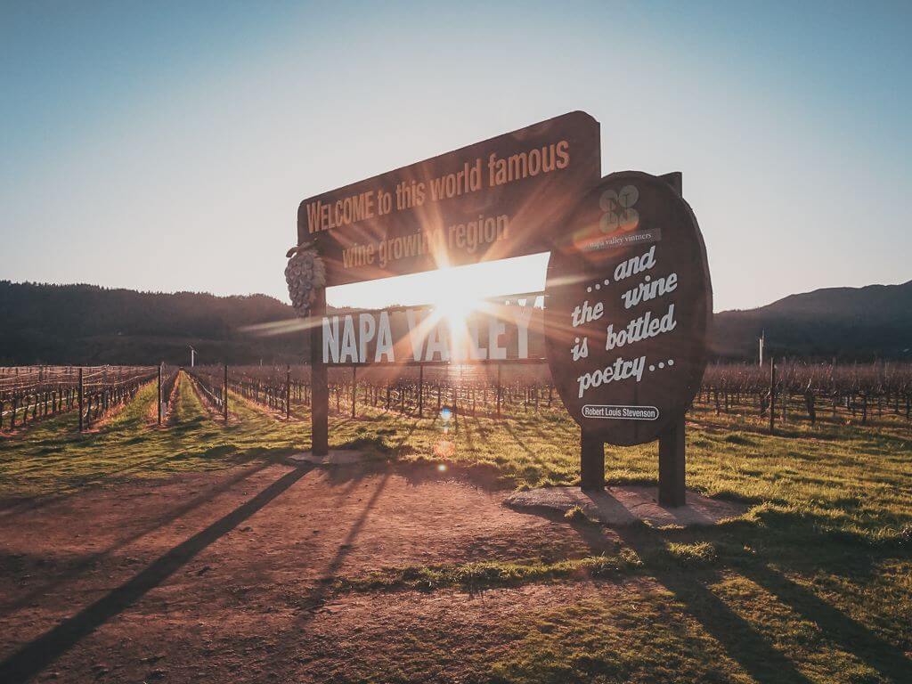 napa valley sign in front of a vineyard at sunset