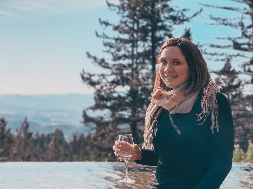 Brunette girl sipping glass of white wine near infinity pool of Cade Estate Winery in Angwin