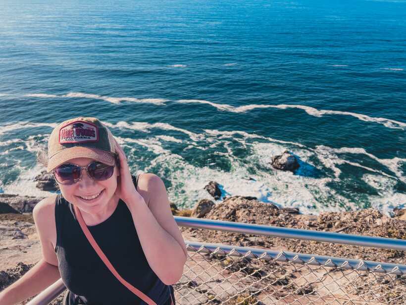 Girl in Muir Woods hat standing above the Pacific ocean in California