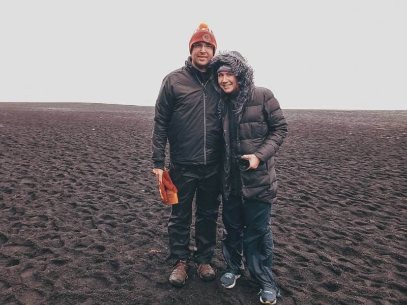 couple dressed in rain and wind proof layers on Iceland black sand beach