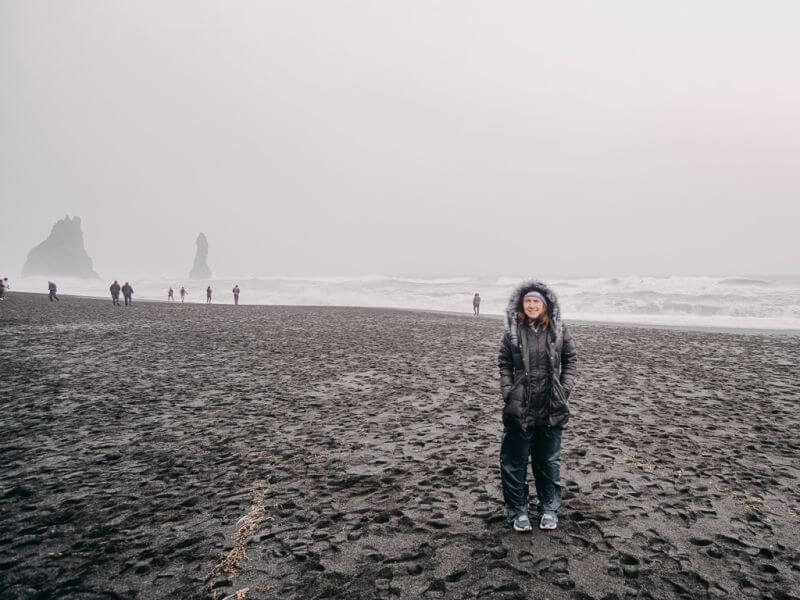 girl bundled up on black sand beach - what to wear in iceland in october