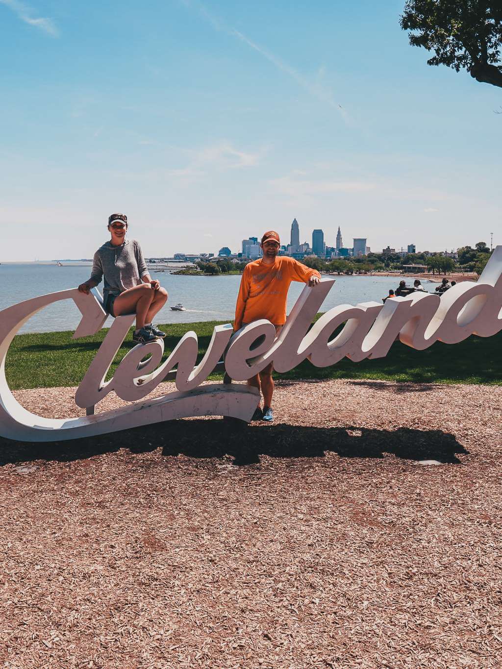 man and woman posing by Cleveland sign with downtown in the background