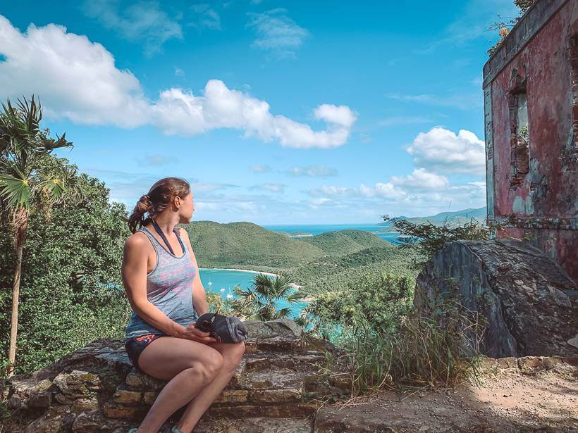 girl sitting on low wall looking out towards Maho Bay and the British Virgin Islands