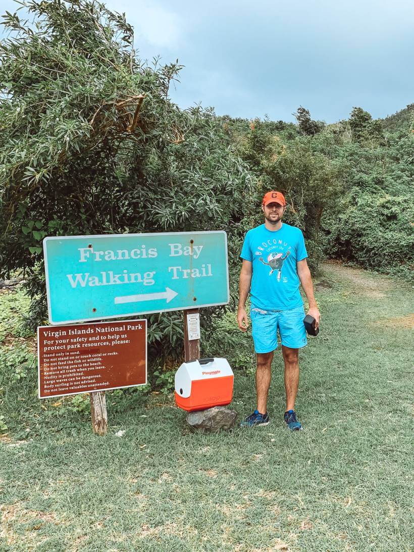 man standing at trailhead of francis bay trail with cooler
