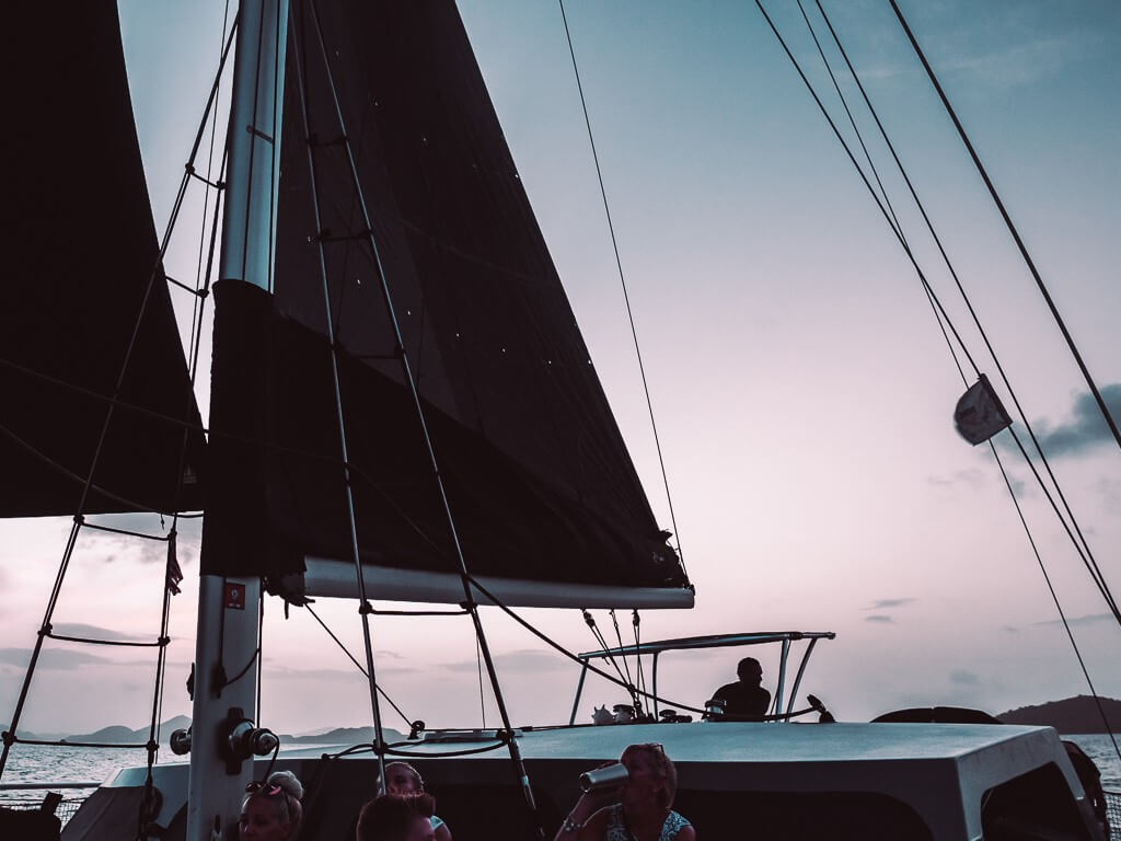 black sails against pink and purple sky on st john sunset cruise