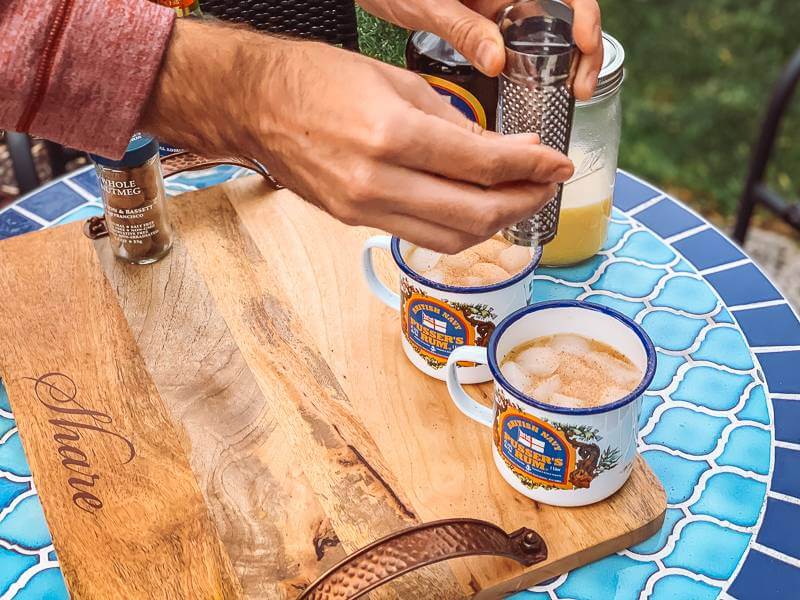 Hand grating nutmeg on top of painkiller cocktails