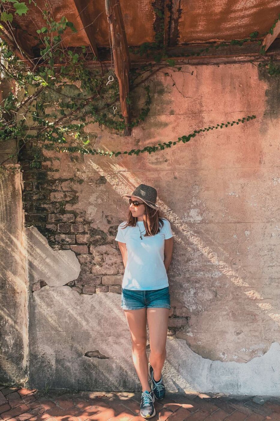 girl in white t-shirt standing in from of plastered brick wall in Savannah