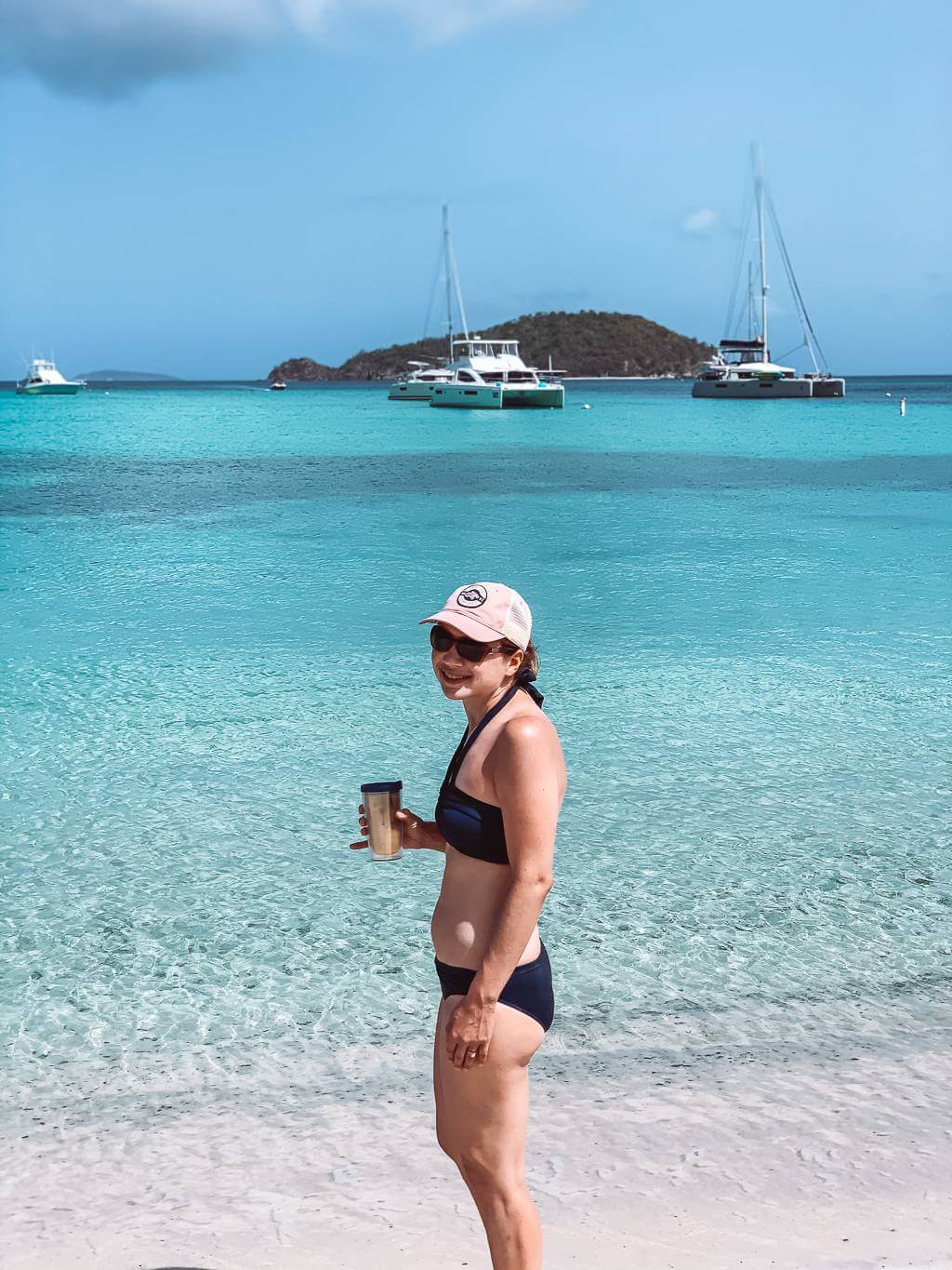 Girl stands at Maho Bay with boats docked in the background - st thomas to st john day trip