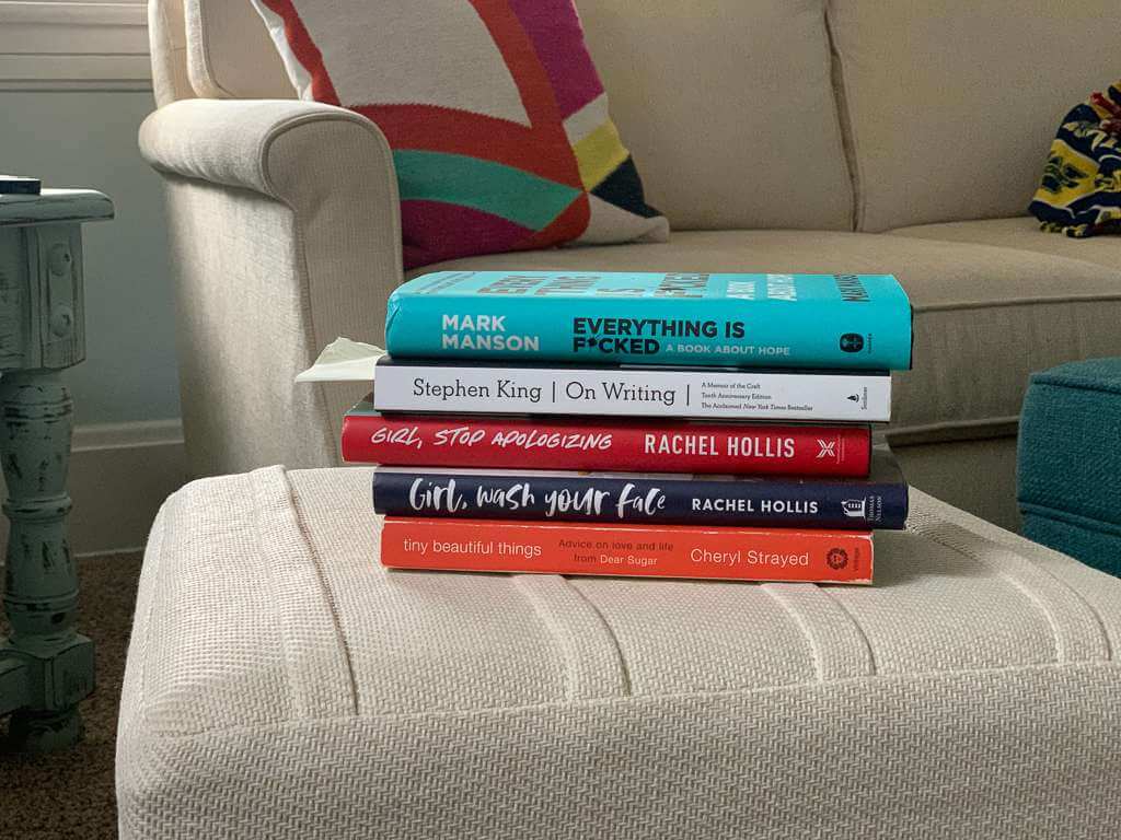 stack of books on beige ottoman