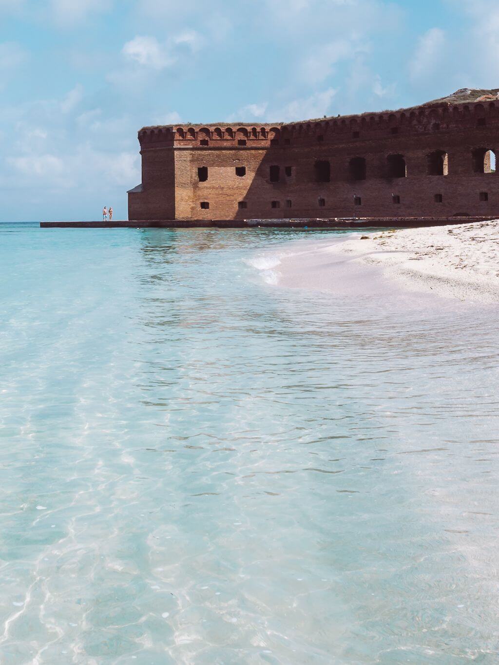 White sand beach with aqua waters at Dry Tortugas National Park with Fort Jefferson in the background