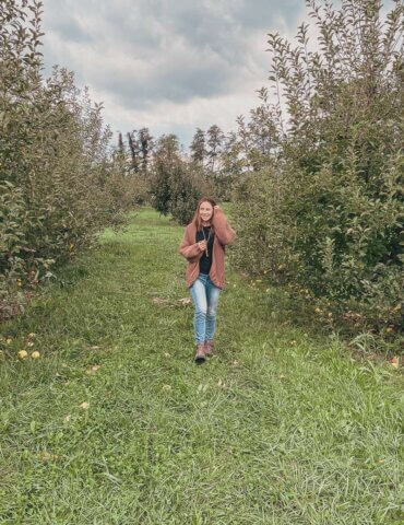 girl walking through orchard wearing pink handmade sweater - 2021 goals fall update
