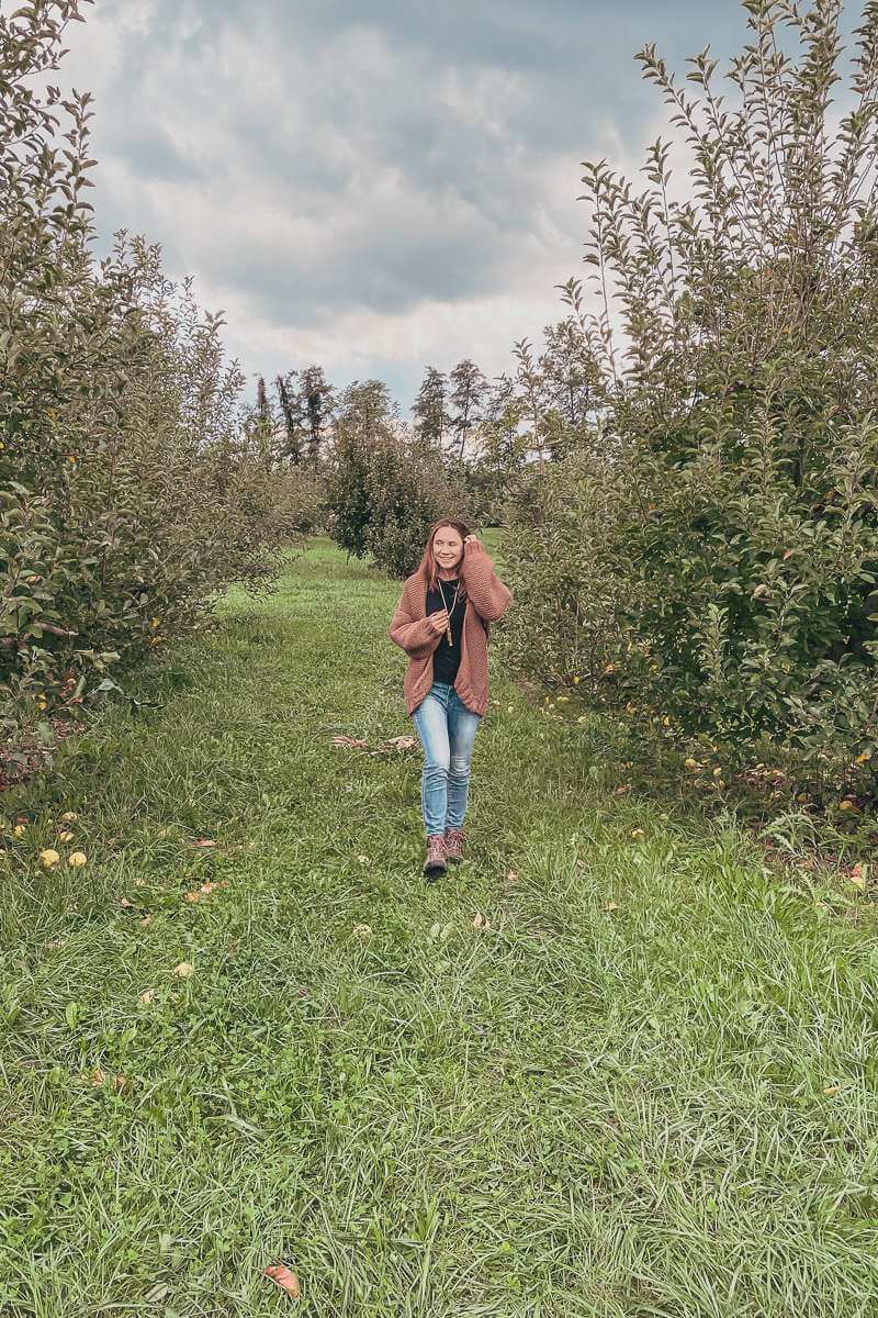 girl walking through orchard wearing pink handmade sweater - 2021 goals fall update