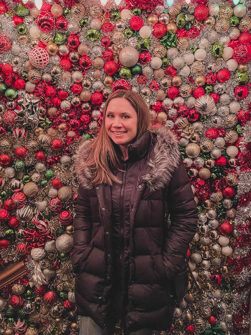 girl standing in front of wall covered in Christmas ornaments