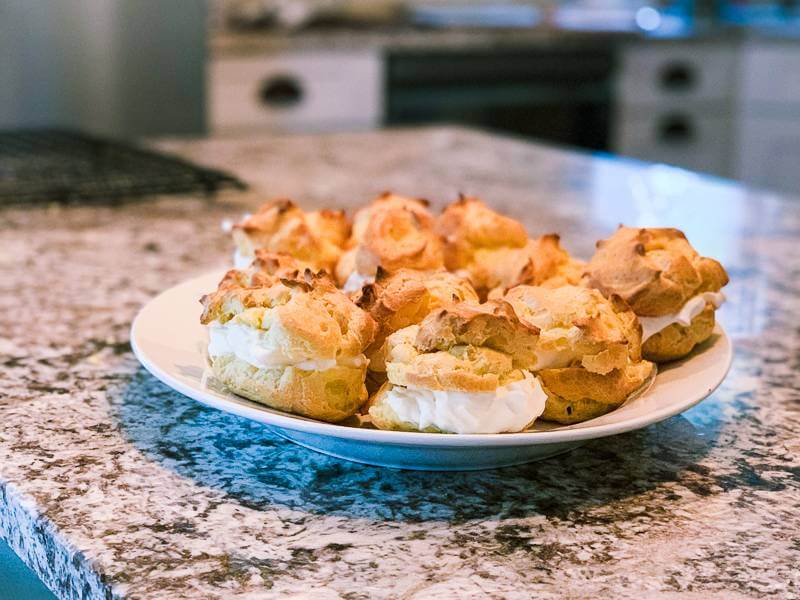 plate of golden cream puffs with whipped cream in the middle