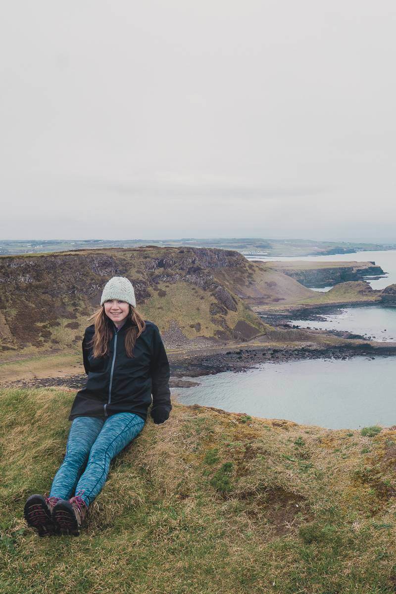 Girl sitting on Giant's Causeway with cliffs in the background - 2022 goals spring update