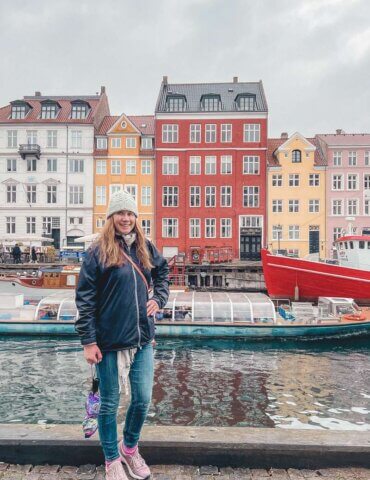 girl in coat and hat standing in nyhavn in Copenhagen during solo travel