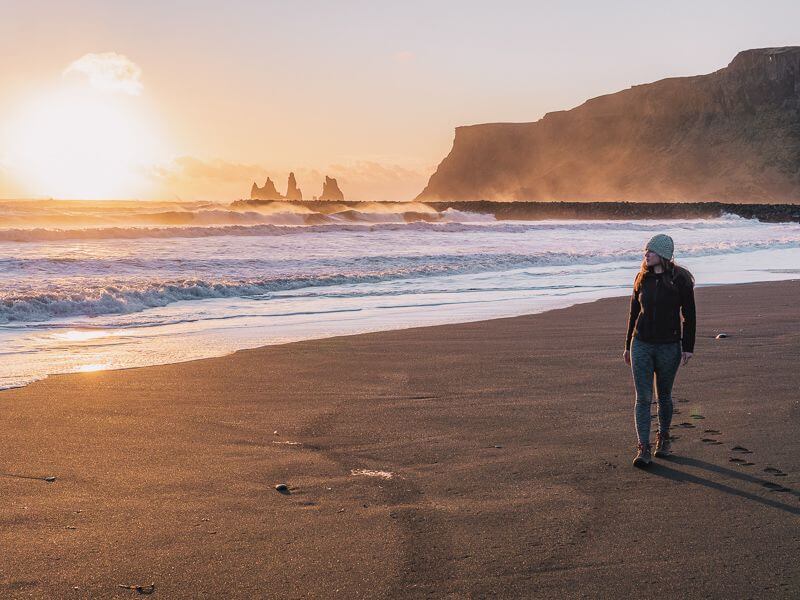 Girl strolling down Vik's black sand beach during Golden Hour