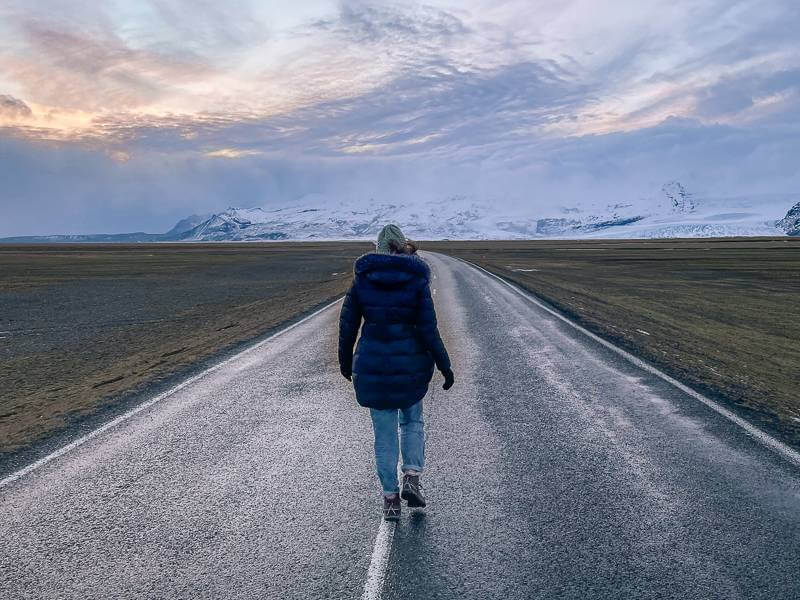 girl walking along empty road in Iceland
