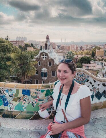 brunette girl sitting by Barcelona city view at Park Guell during solo travel