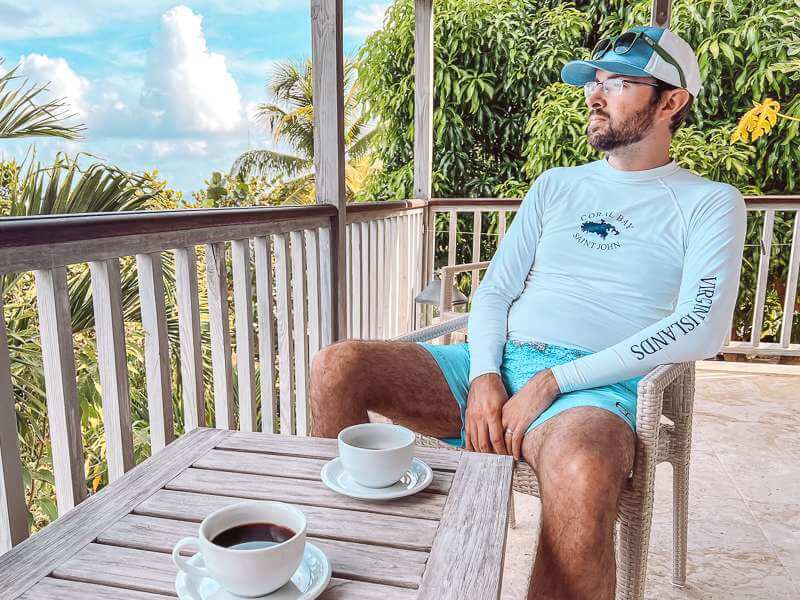 Man enjoying view from suite at Cooper Island Beach Club with cup of coffee
