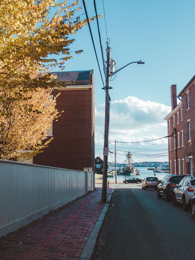 View past red brick buildings on Salem street out to the harbor, where there is an old ship