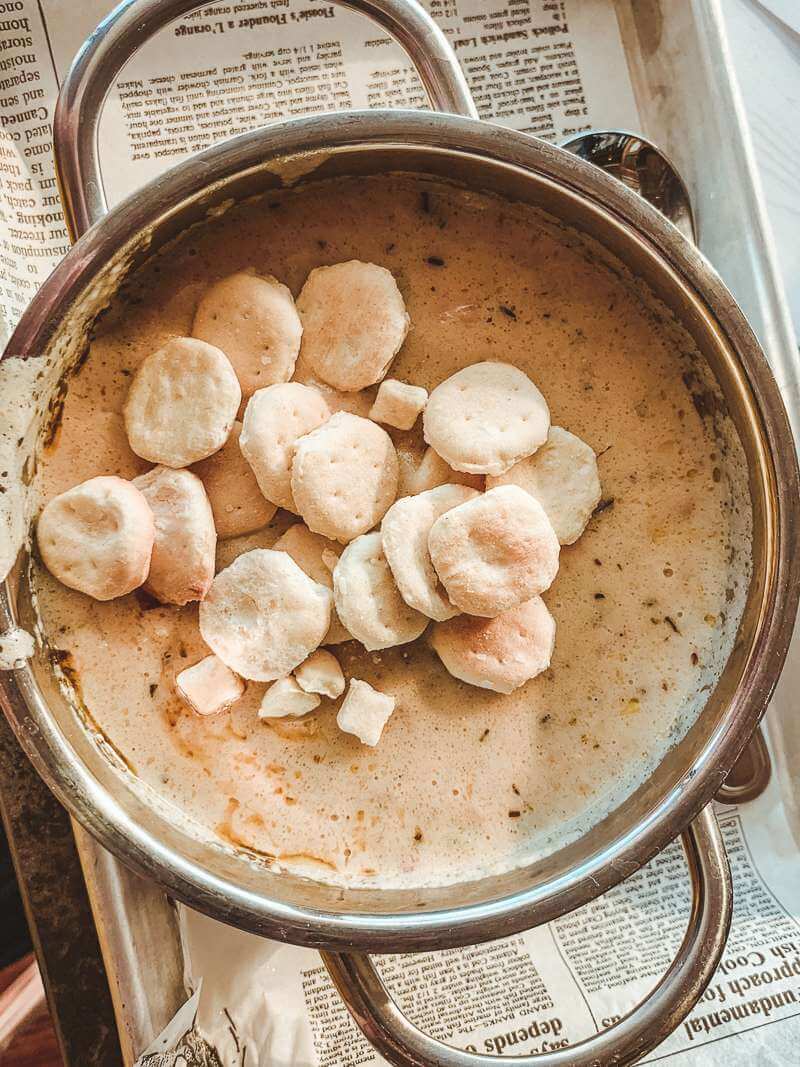 Warm metal bowl of clam chowder with oyster crackers