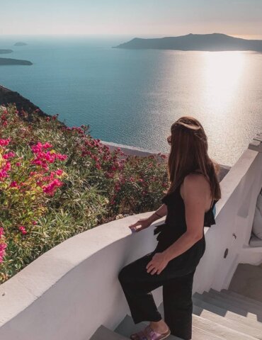 Brunette girl in black romper overlooking caldera during Santorini itinerary