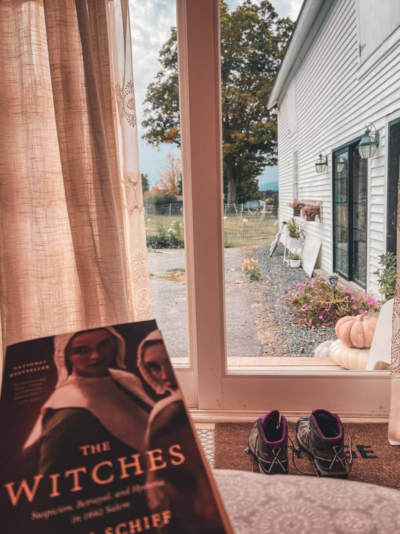 Book The Witches being held in front of patio window with pumpkins and farm