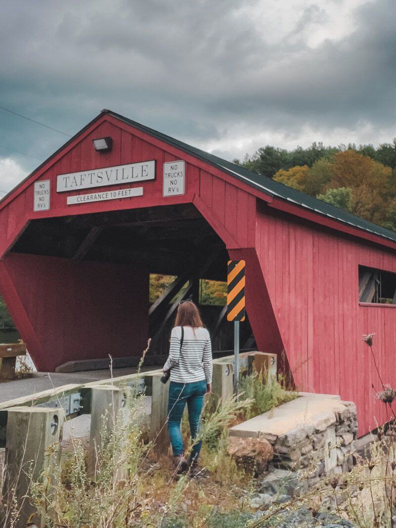 Girl walking towards red covered bridge in Vermont