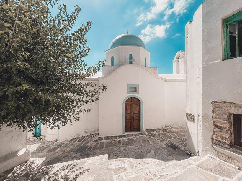 Small white church with light blue dome in Lefkes on Paros