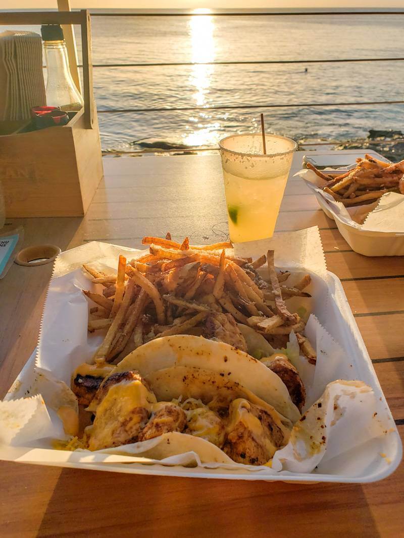 Plate of tacos and truffle fries while dining at Rhythms at Rainbow Beach during sunset