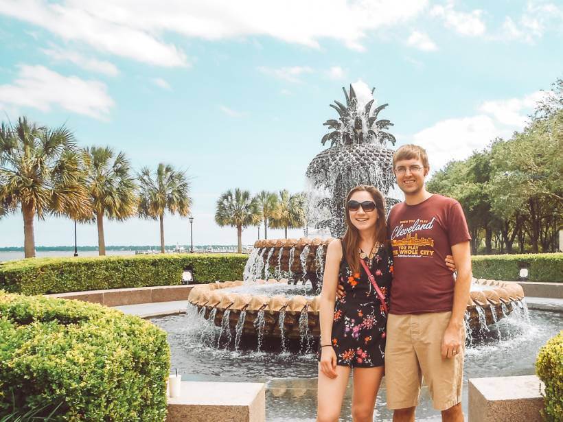 Couple standing in front of pineapple fountain at waterfront park in Charleston SC